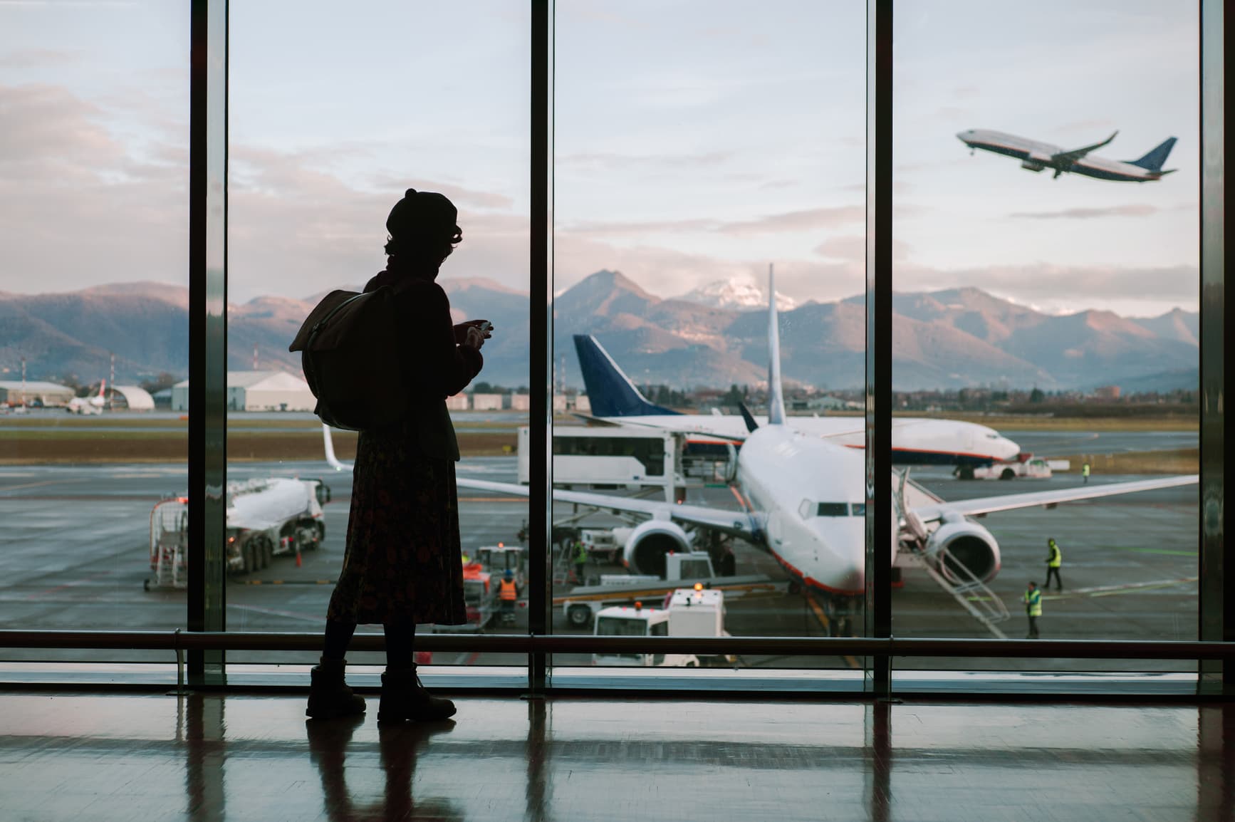 Silhouette of a passenger with a backpack on the background of a panoramic view of the aircraft parking